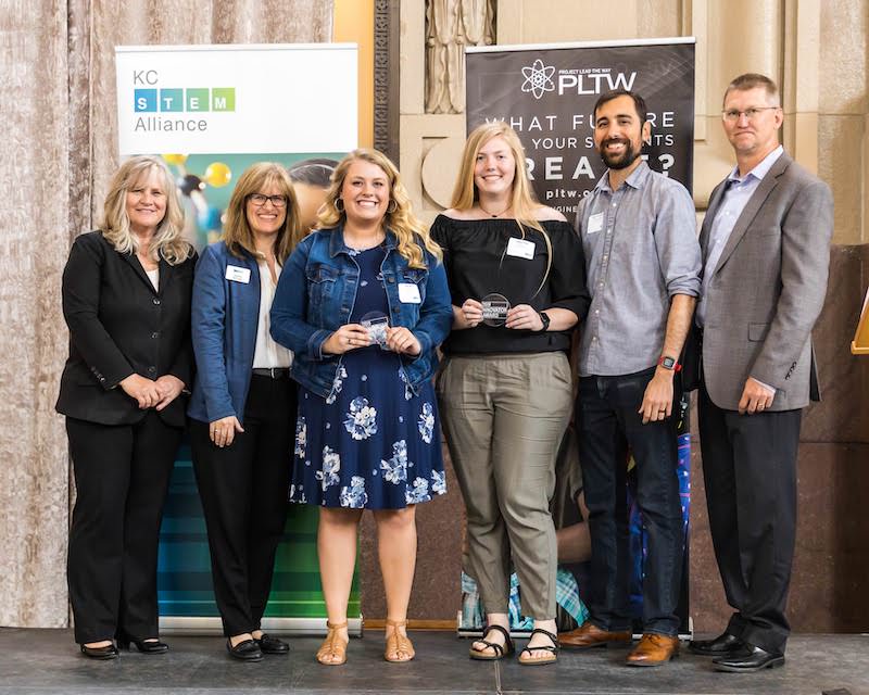 Students posing with award on stage