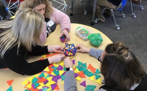 Three female teachers work with math manipulative