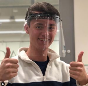 Teen boy wearing face shield and showing two thumbs up